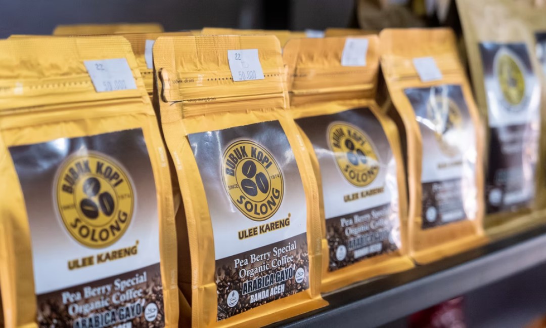 A shelf full of packaged coffee in yellow bags.
