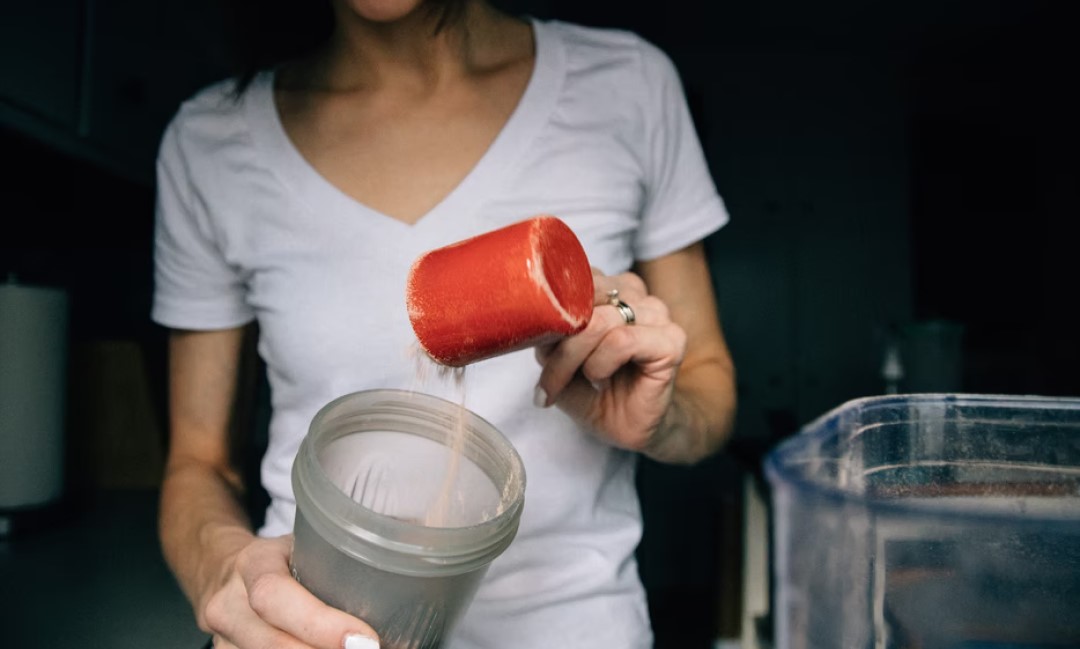 A woman mixing protein powder into her morning drink.